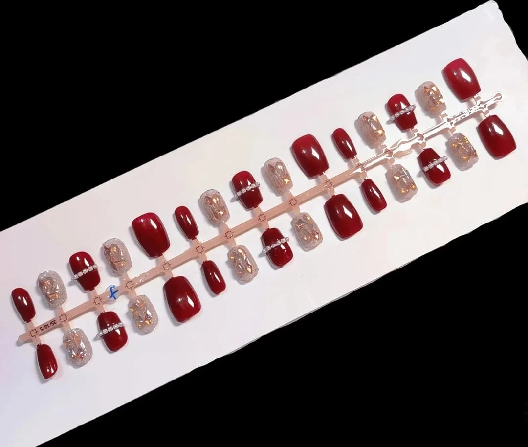 Røde trykk-on negler med kjede og aurora-rhinestones, kort ballerinaform